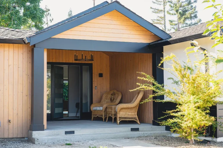 Custom home building project with a modern wood entry, covered porch, and black trim
