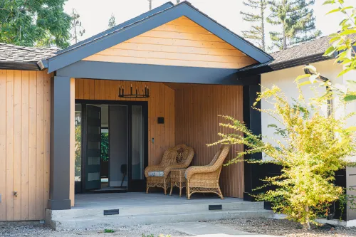 Custom home building project with a modern wood entry, covered porch, and black trim