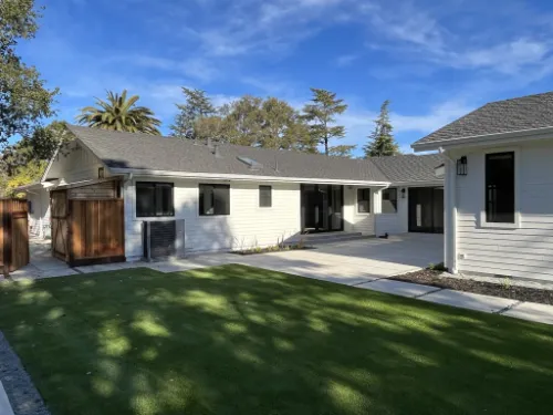 Exterior design project with a remodeled home, patio, lawn, and detached backyard structure