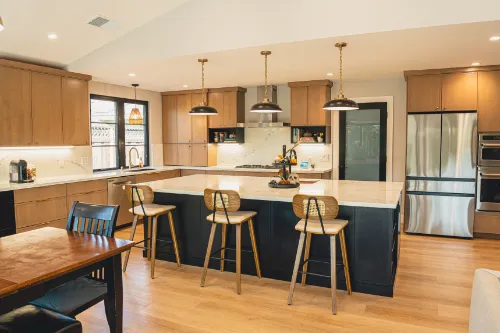 Kitchen remodeling project with wood cabinetry, black island, quartz countertops, pendant lights, and open dining area